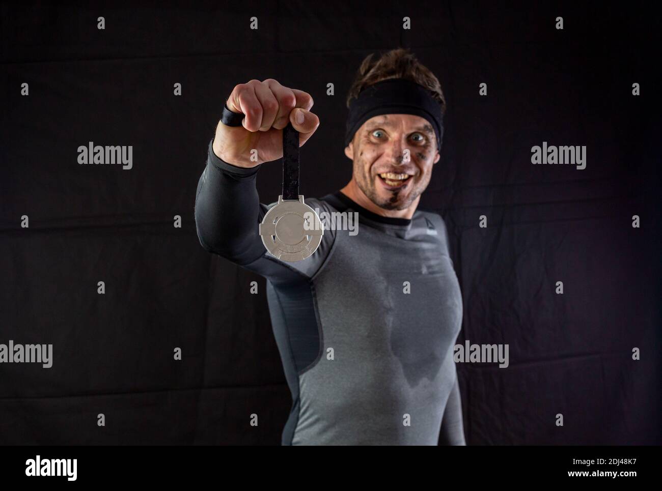 Handsome man in sportswear is insanely rejoicing at the received silver medal in the studio on a black background Stock Photo