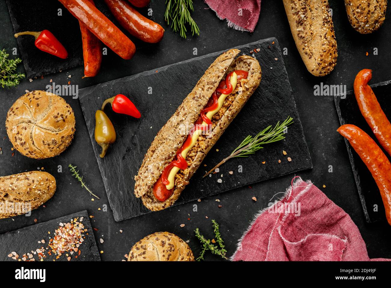 Flat lay composition of delicious hot dogs and sandwiches with different toppings on the dark background Stock Photo