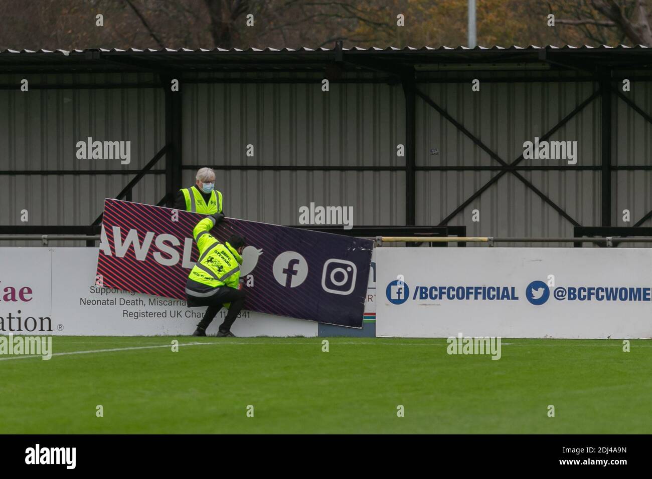Solihull, West Midlands, UK. 13th Dec, 2020. Rain has caused the postponement of the Womens Super League match between Birmingham City women and Everton FC women at Solihull Moors ground. Staff demount the WSL hoardings. Credit: Peter Lopeman/Alamy Live News Stock Photo