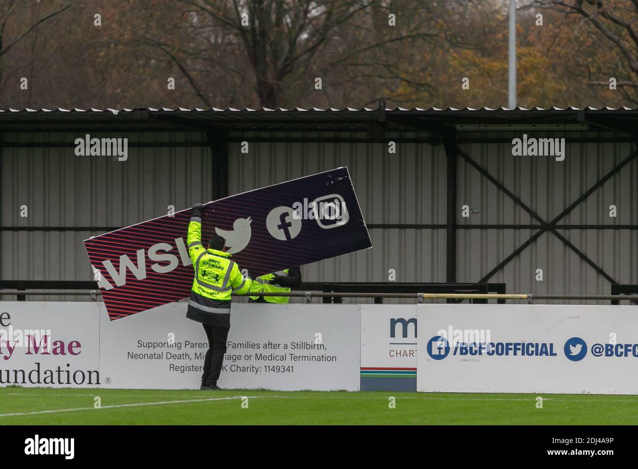 Solihull, West Midlands, UK. 13th Dec, 2020. Rain has caused the postponement of the Womens Super League match between Birmingham City women and Everton FC women at Solihull Moors ground. Staff demount the WSL hoardings. Credit: Peter Lopeman/Alamy Live News Stock Photo