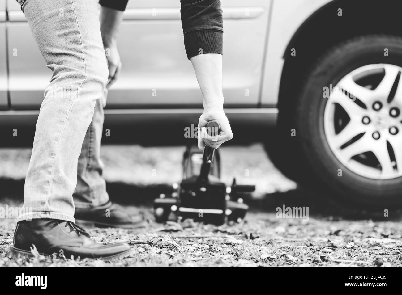A greyscale shot of a mechanic trying to fix a car with special tools Stock Photo