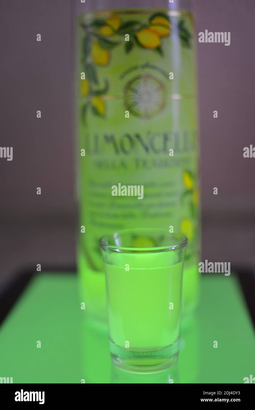 Glass and Bottle of Limoncello standing on a lightblue background