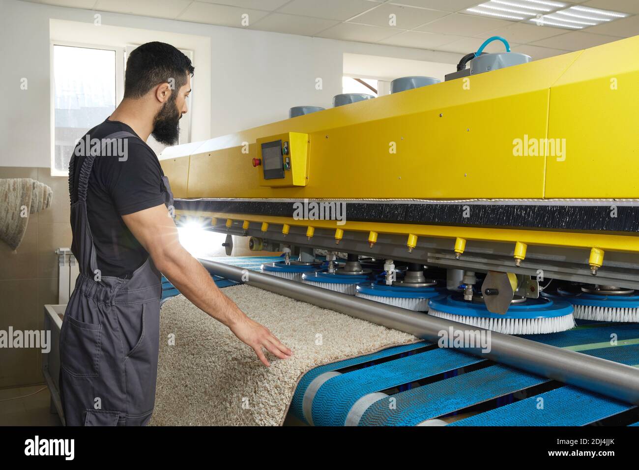 Man operating carpet automatic washing machine in professional laundry service Stock Photo
