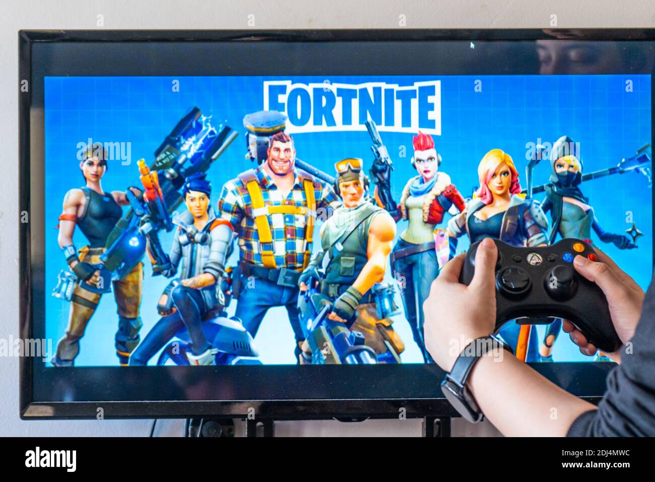 Woman holding a xbox controller and playing popular video game Fortnite on  a television and PC Stock Photo - Alamy