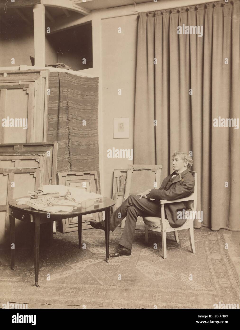 Whistler Seated in a Chair in His Paris (rue Notre-Dame-des-Champs) Studio, Paul François Arnold Cardon, called 'Dornac', 1859–1941, French, 1893, Albumen print on thin, smooth, wove paper, Sheet: 10 1/4 x 8 inches (26 x 20.3 cm) and Mount: 17 × 14 inches (43.2 × 35.6 cm), artist, books, bottle, box, chair, coat, collar, curtains, drawer (furniture component), man, painter, paintings, paper, portrait, printmaker, rafters, rug, shoes, studio (work space), table, tie, trousers, vest, Europe, France, Paris Stock Photo