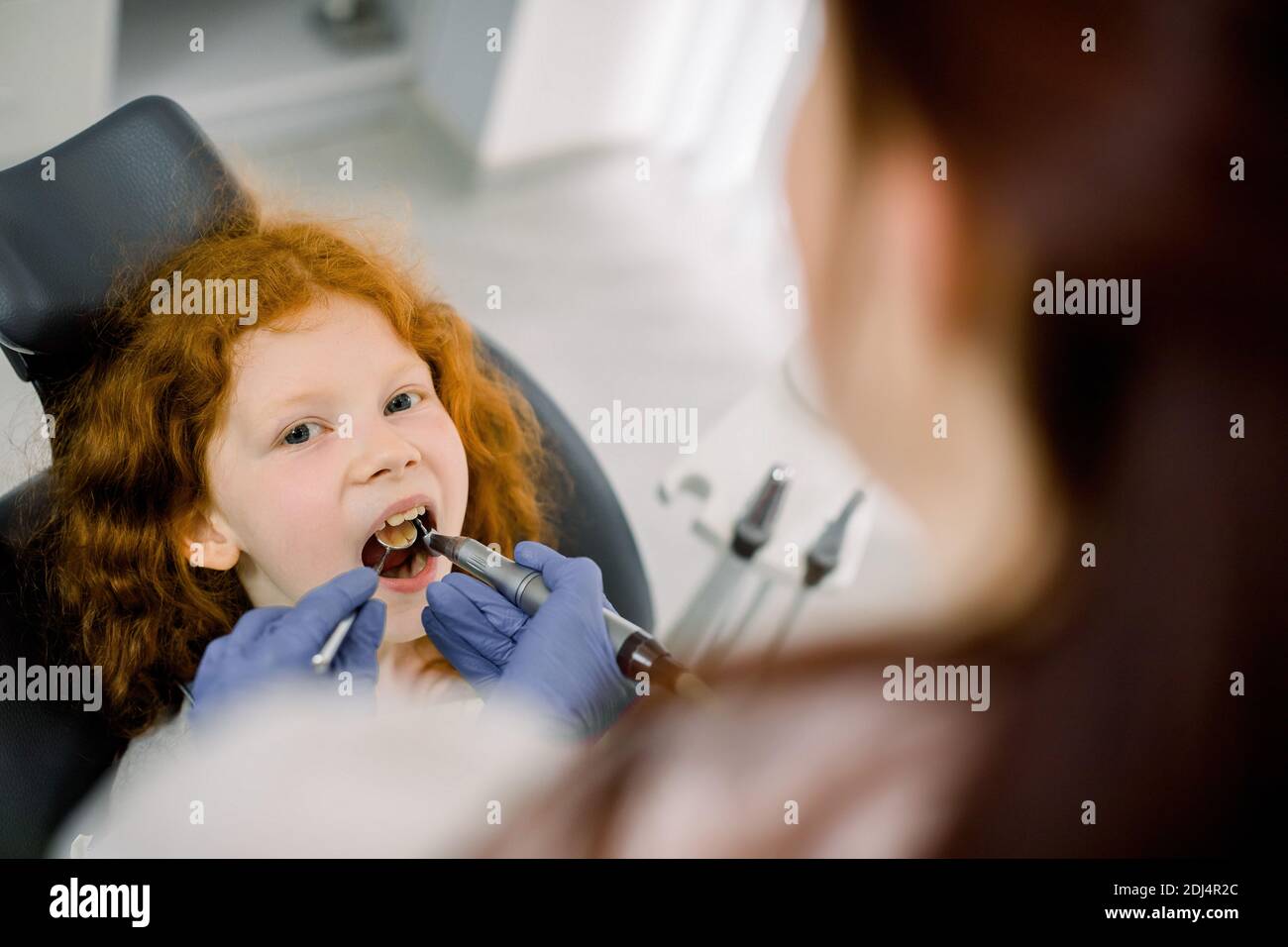 Cute pretty little red haired girl during the dental procedure at the