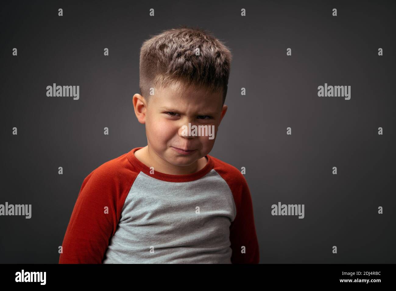 Angry boy frowning, showing with his face dislike isolated on grey background. Fake child emotions. Human emotions, facial expression concept. Facial Stock Photo