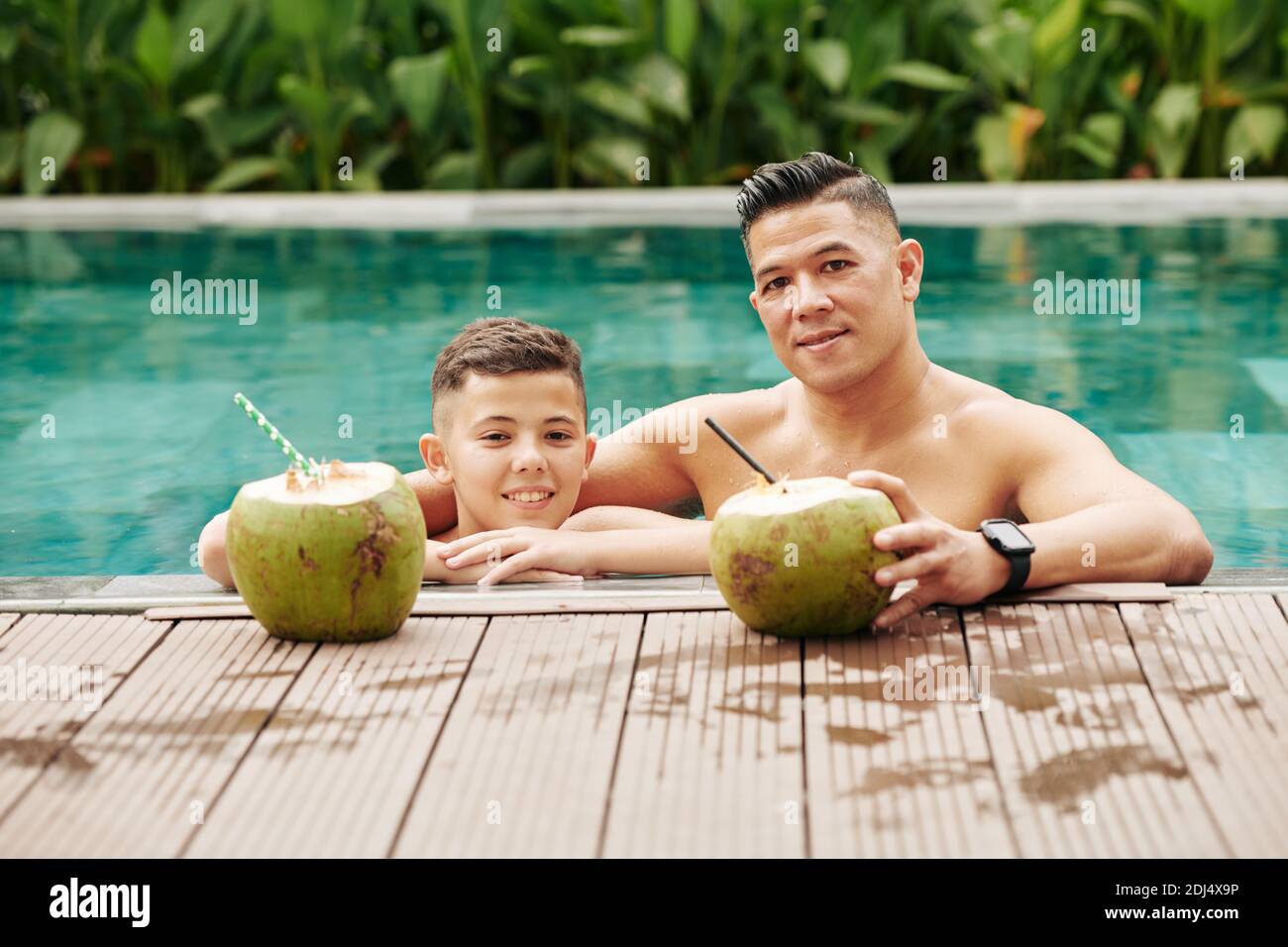 Father And Preteen Son Spending Time In Swimming Pool And Enjoying