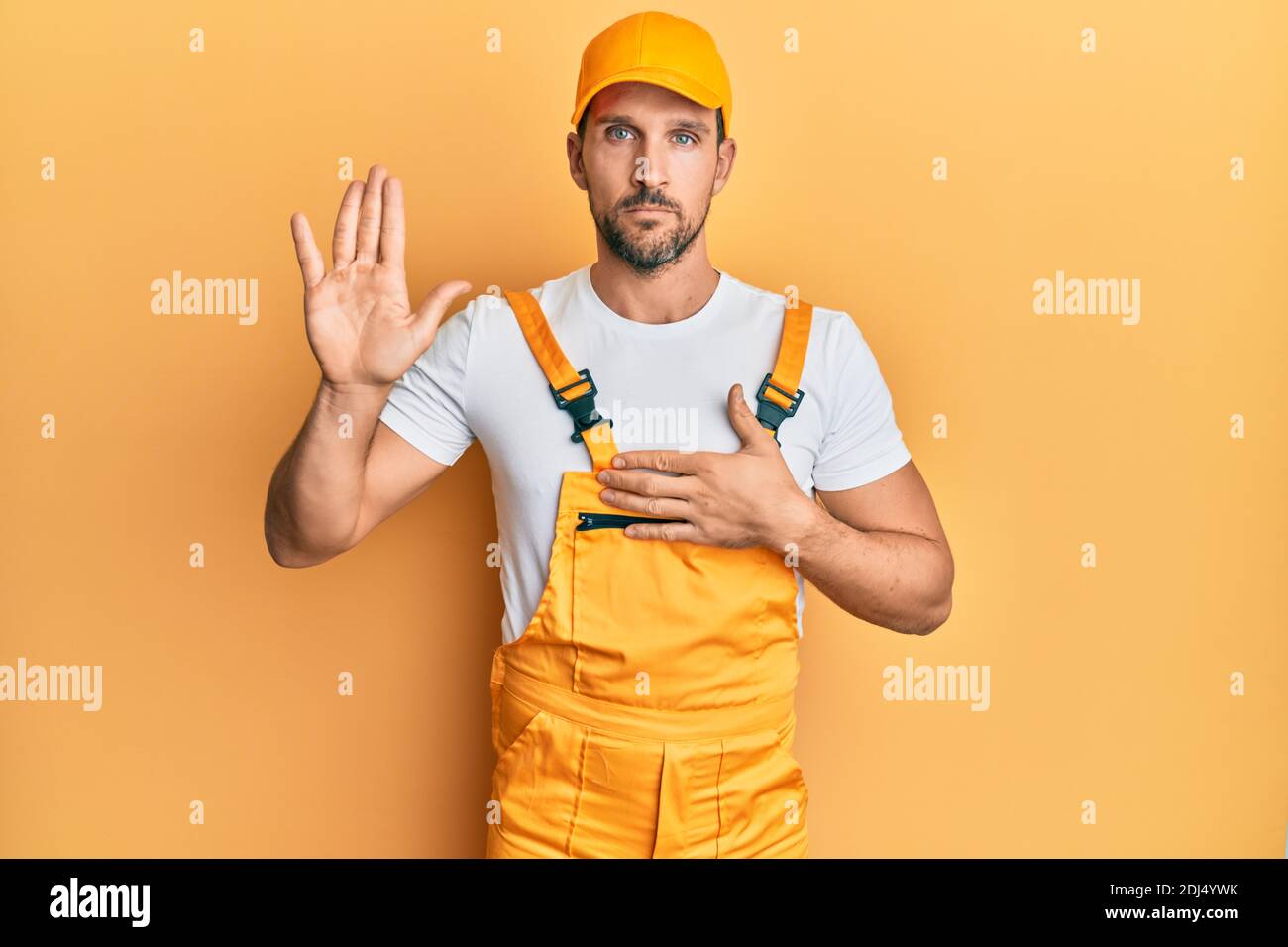 Young handsome man wearing handyman uniform over yellow background ...