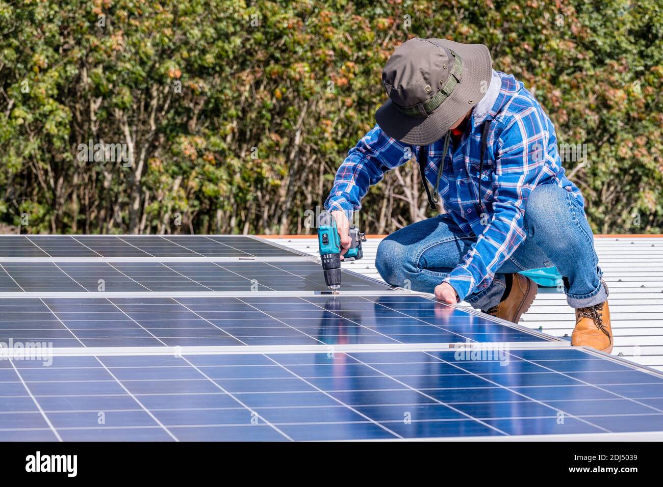 man installing solar panels on a home rooftop for alternative energy photovoltaic safe energy. power from nature sun power solar cell generator. Stock Photo