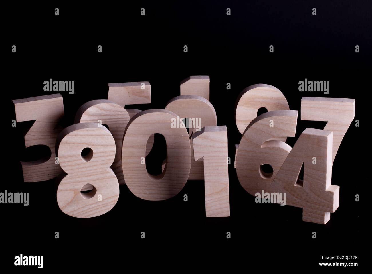 Large random wooden numbers standing up overlapping. Hardwood characters on a black background with copy space Stock Photo