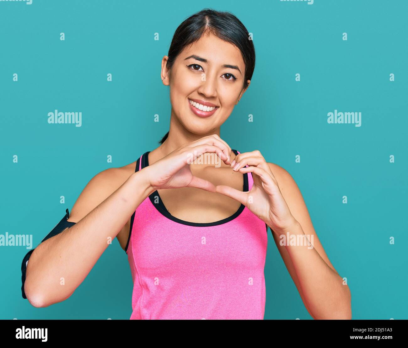 Beautiful asian young sport woman wearing sportswear and arm band smiling  in love doing heart symbol shape with hands. romantic concept Stock Photo -  Alamy