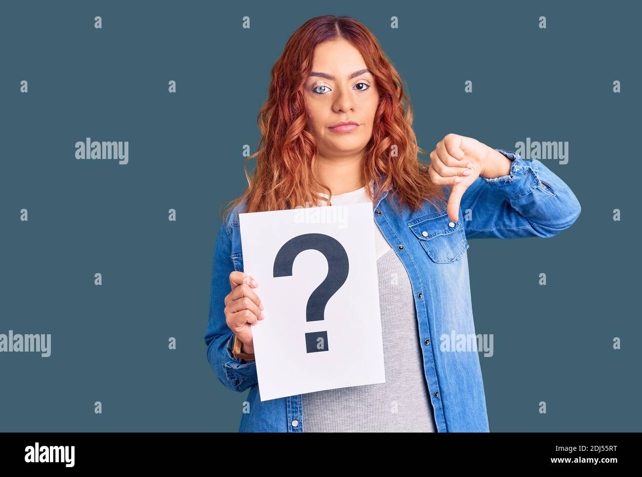 Young latin woman holding question mark with angry face, negative sign ...