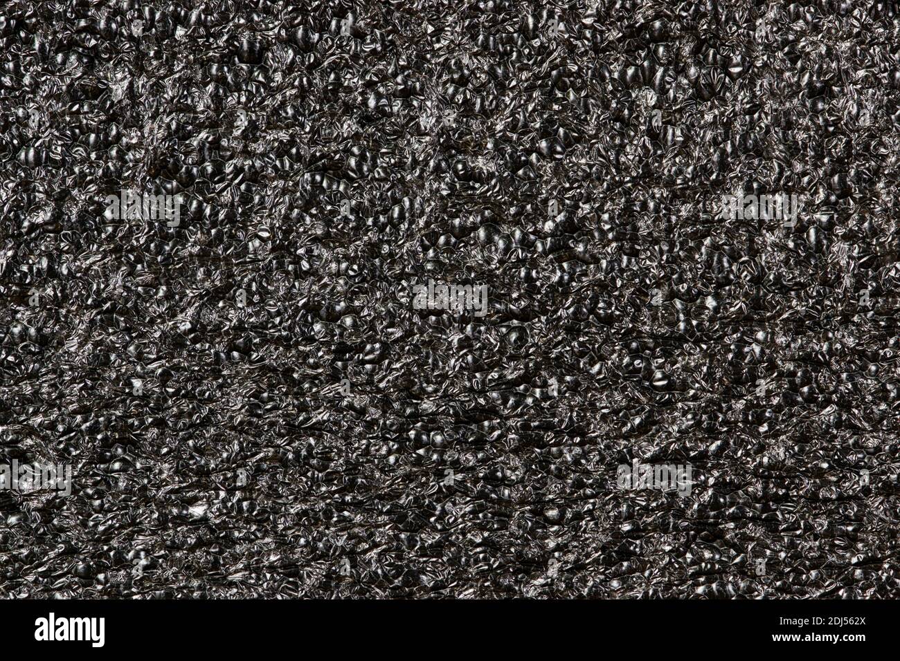 Black Expanded polyethylene foam sample background. EPE beads packing material with macro details, textures and one solid color. Stock Photo