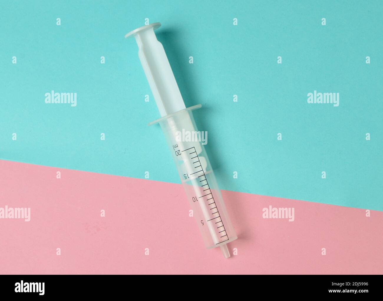 A medical syringe without a needle on a pastel background, top view, minimalism. Medical equipment. Stock Photo