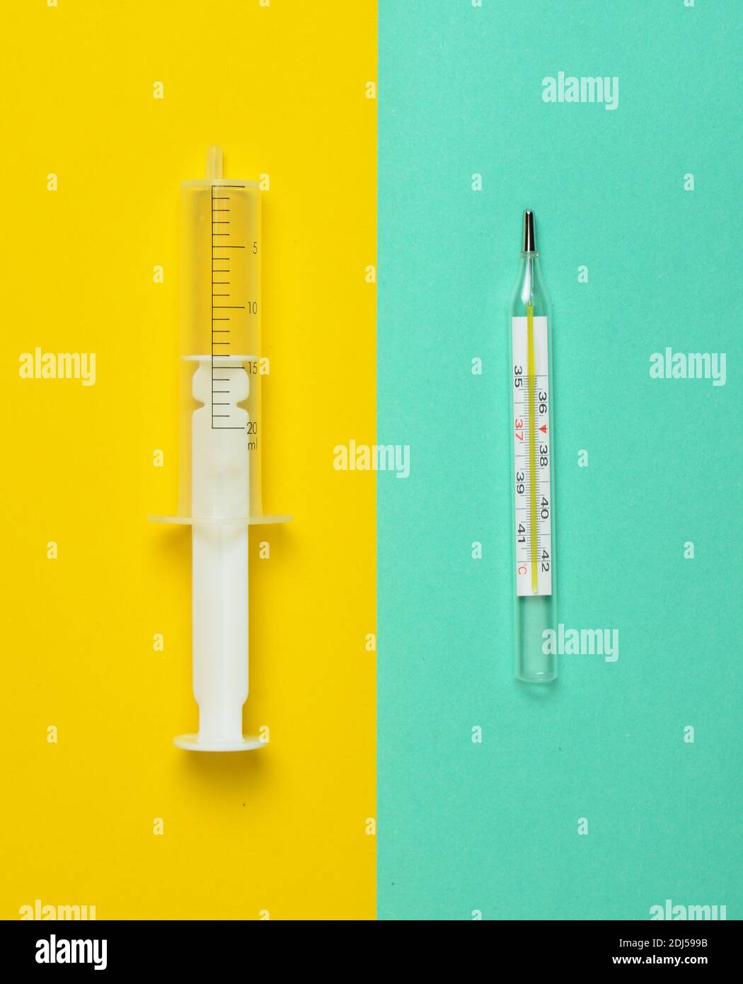 A medical syringe without a needle and a thermometer on a pastel background, top view, minimalism. Medical equipment. Stock Photo