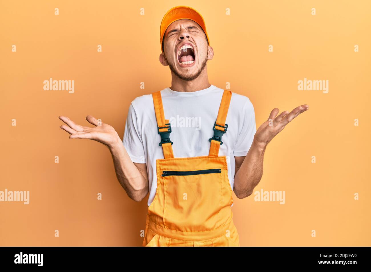 Hispanic young man wearing handyman uniform celebrating mad and crazy ...