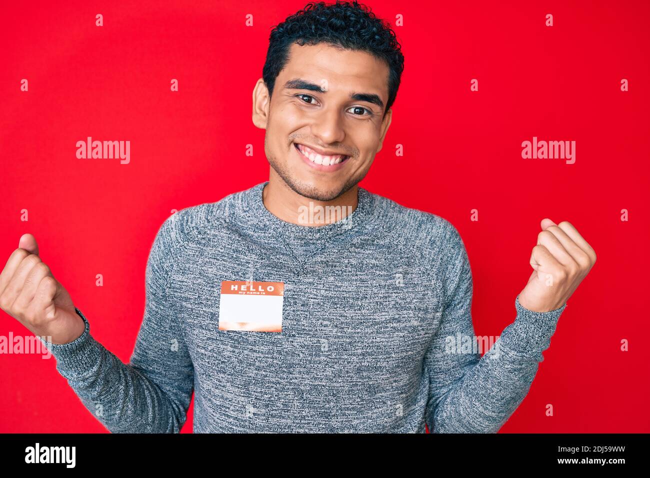 Young handsome hispanic man wearing hello my name is sticker ...