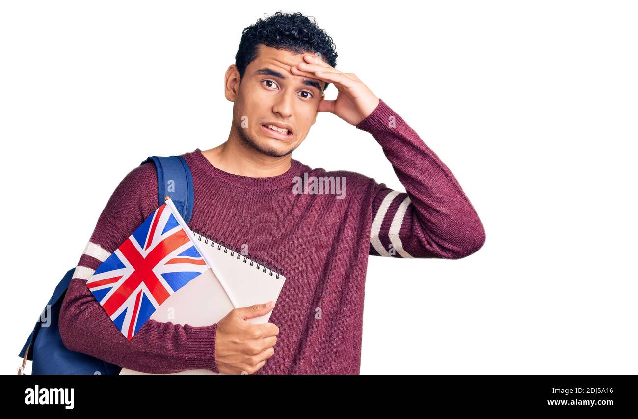 Hispanic handsome young man exchange student holding uk flag stressed and frustrated with hand on head, surprised and angry face Stock Photo