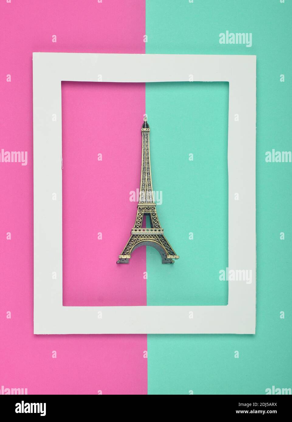 Souvenir statuette of the Eiffel tower in a white frame on a colored pastel background. Minimalist trend. Top view. Stock Photo