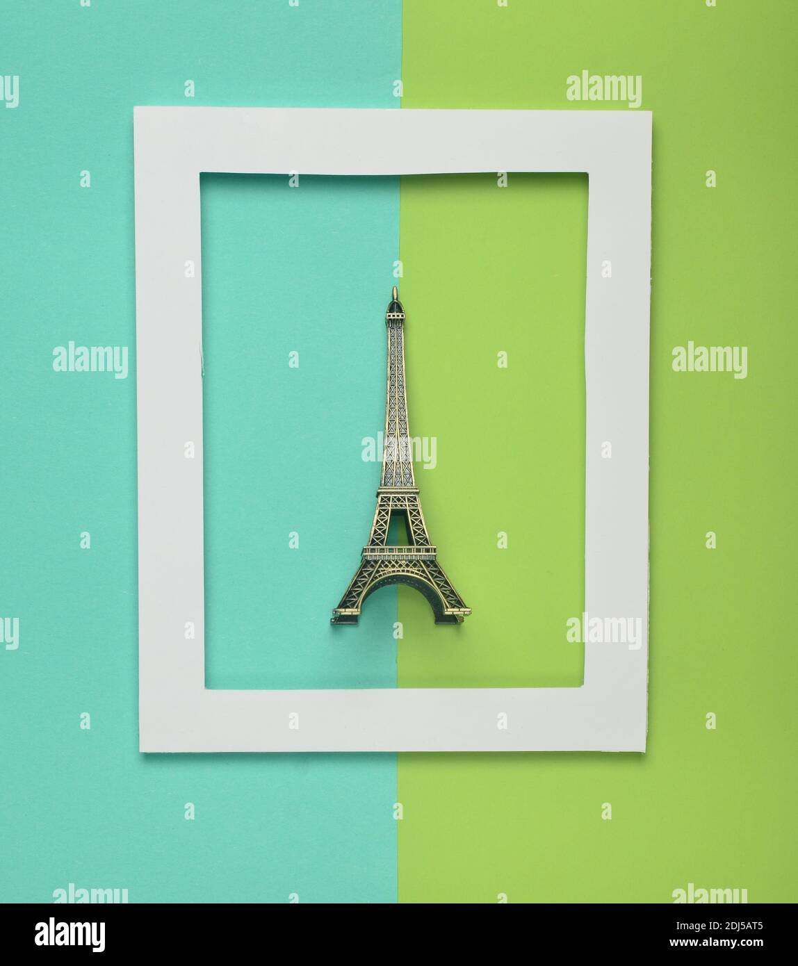 Souvenir statuette of the Eiffel tower in a white frame on a colored pastel background. Minimalist trend. Top view. Stock Photo