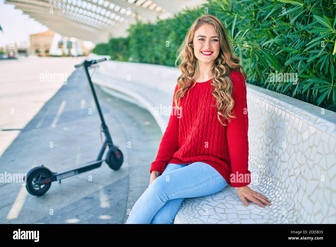 Young blonde girl smiling happy sitting on the bench at the park Stock ...