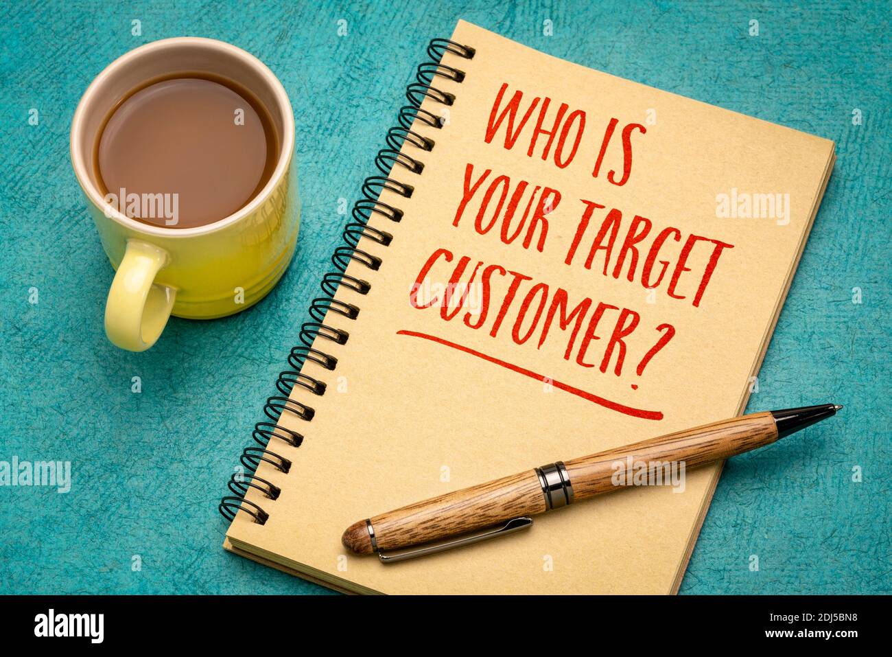 Who is your target customer? Handwriting in a notebook with a cup of