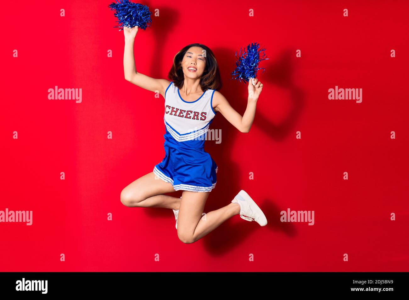 Young beautiful chinese girl smiling happy wearing cheerleader uniform