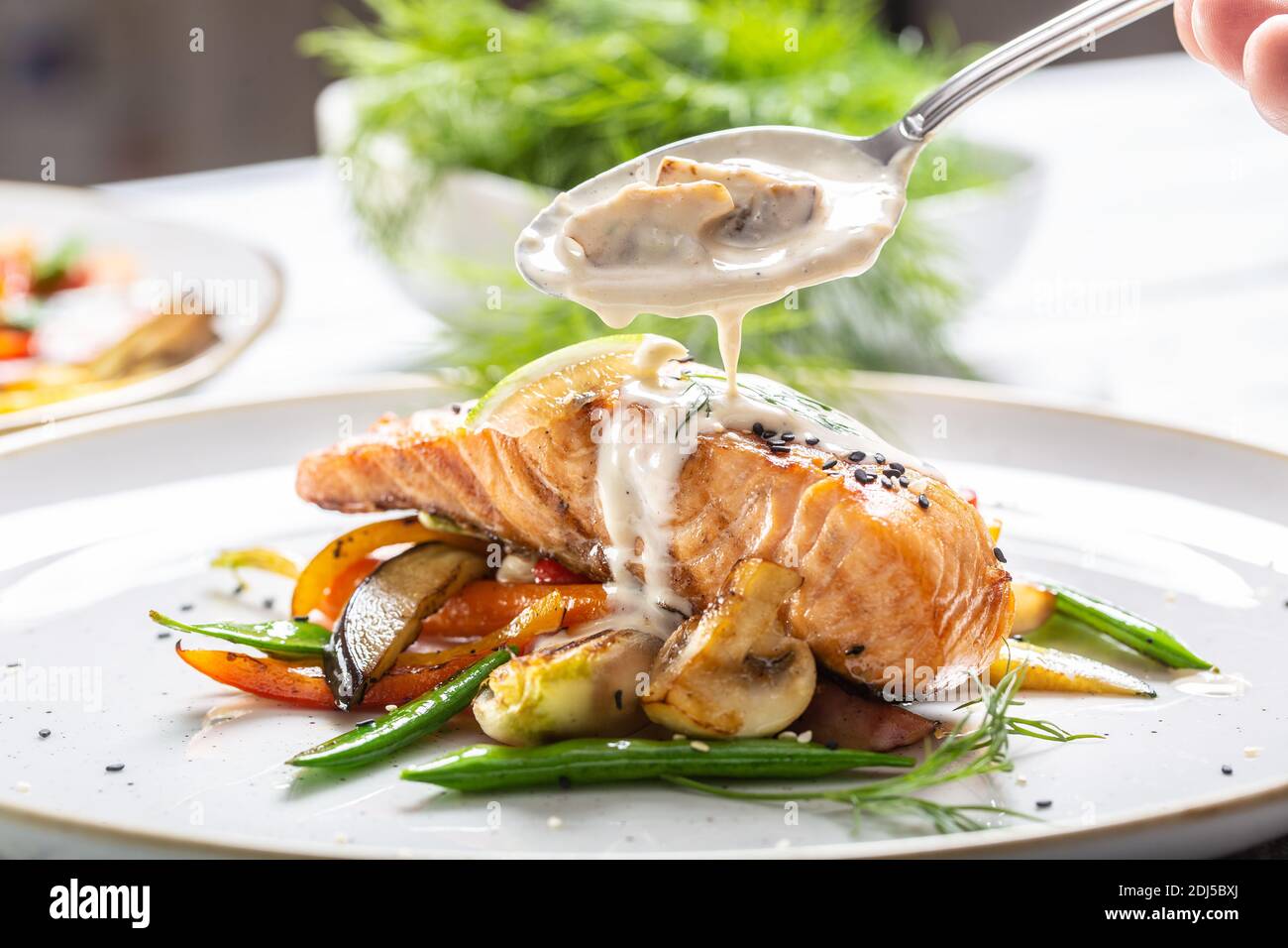 Grilled salmon with vegetables and mushroom sauce poured over it in a