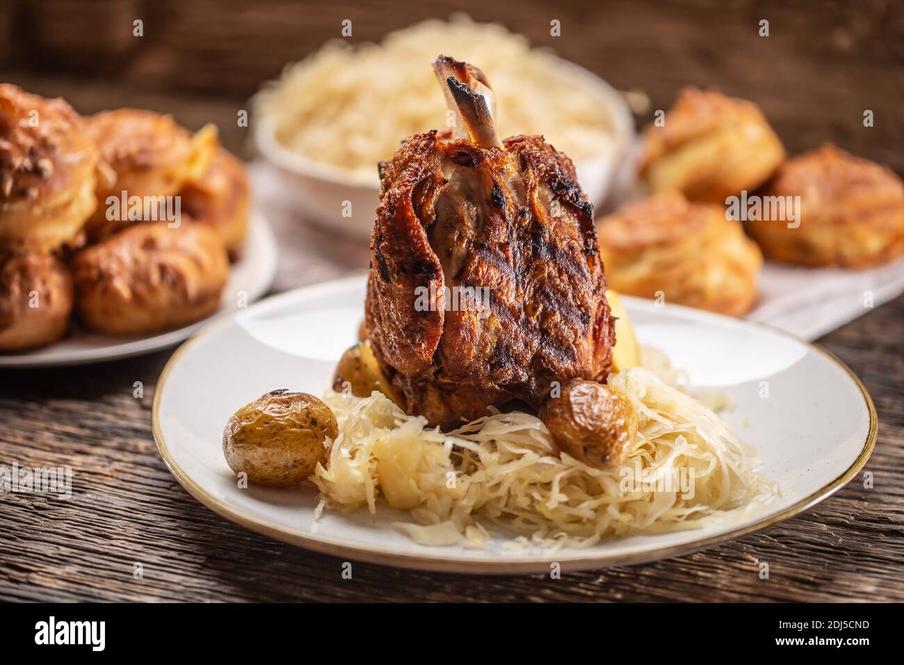 Bavarian pork knuckle with sauerkraut and baked potatoes. Stock Photo