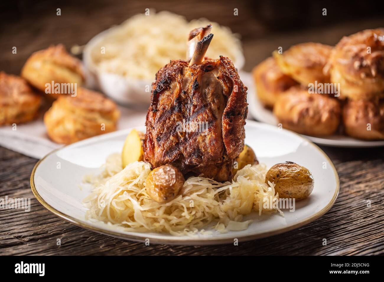 Baked pork knuckle served with sauerkraut and baked pastry. Stock Photo