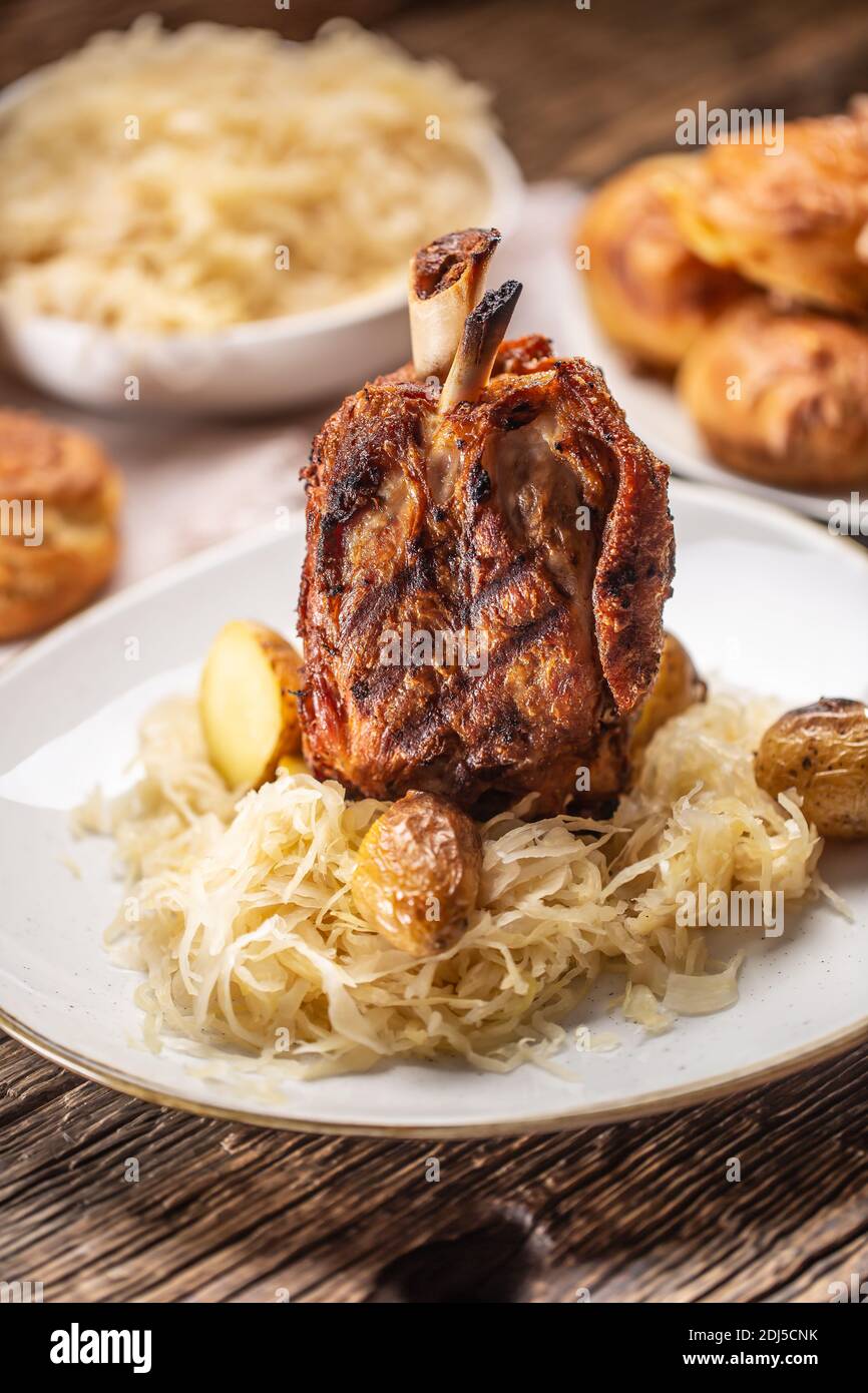German pork knuckle with sauerkraut and baked potatoes. Stock Photo