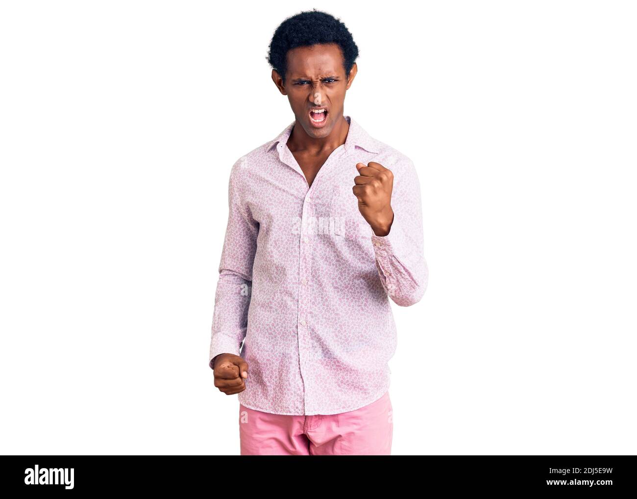 African handsome man wearing casual pink shirt angry and mad raising ...