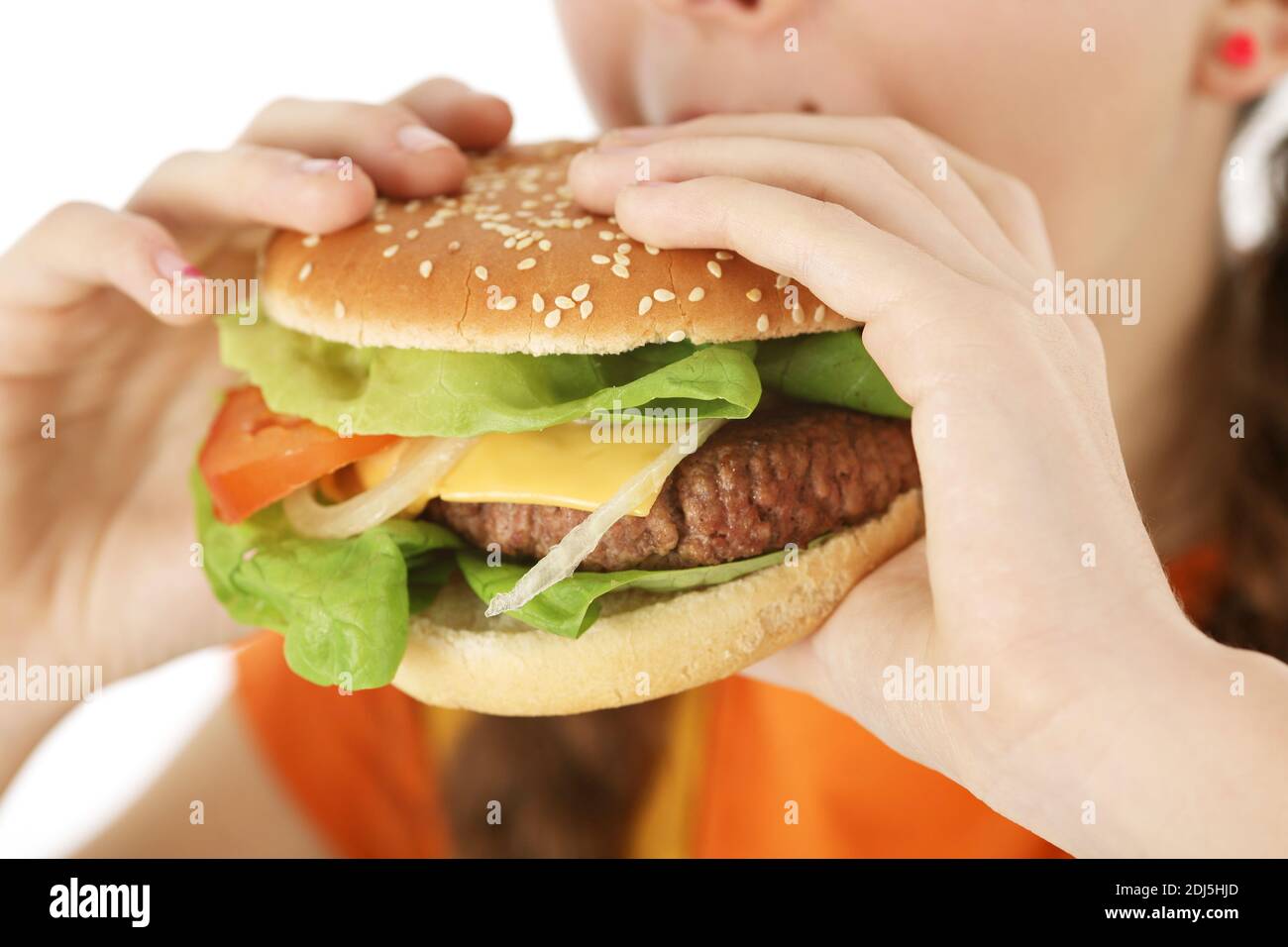 close-up young girl eating a delicious hamburgers or sheeseburger with both hands close-up. Fast food concept photographed on white background - Stock Image