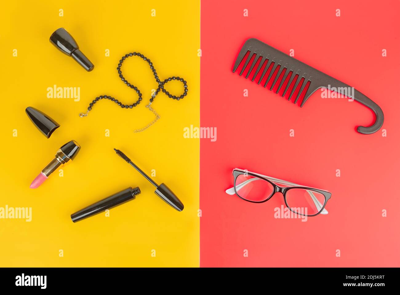 Elegant set of accessory for women. Glasses, cosmetics, jewelry and comb on a yellow and red background. Stock Photo