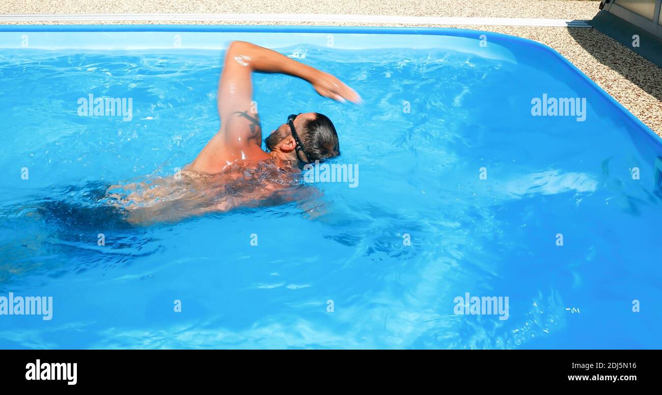 A young man trains in a home pool. Athlete swims in countercurrent ...