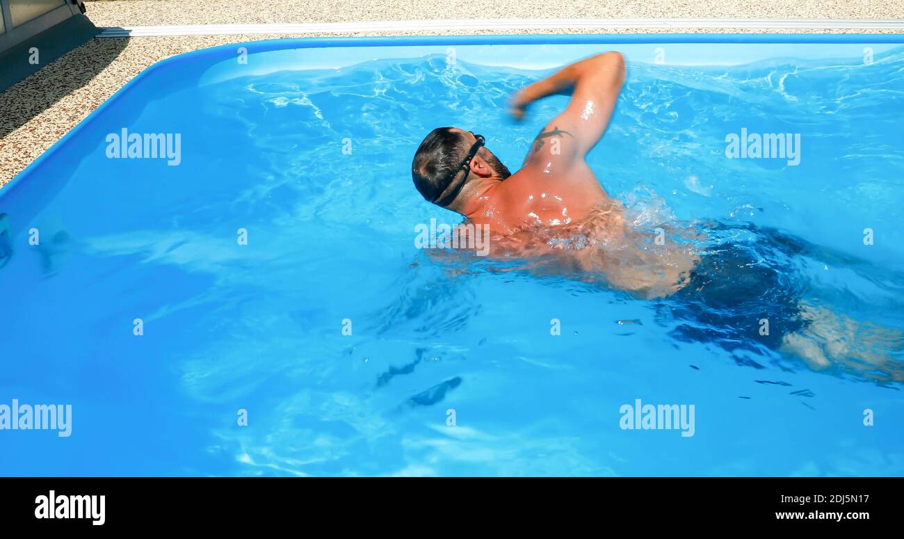 A young man trains in a home pool. Athlete swims in countercurrent ...