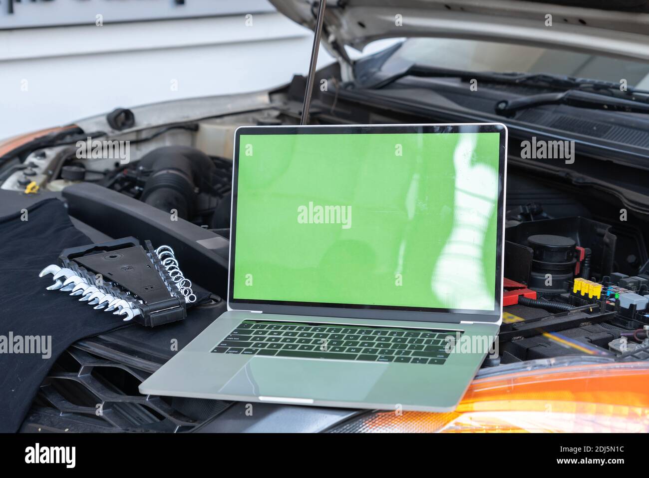 Laptop computer on car hood for engine diagnostic. Car garage repair