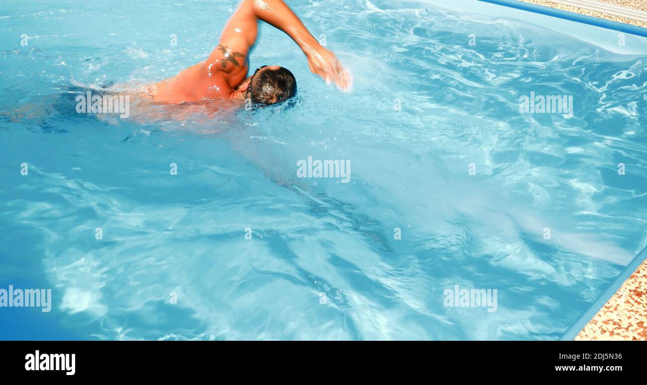A young man trains in a home pool. Athlete swims in countercurrent ...