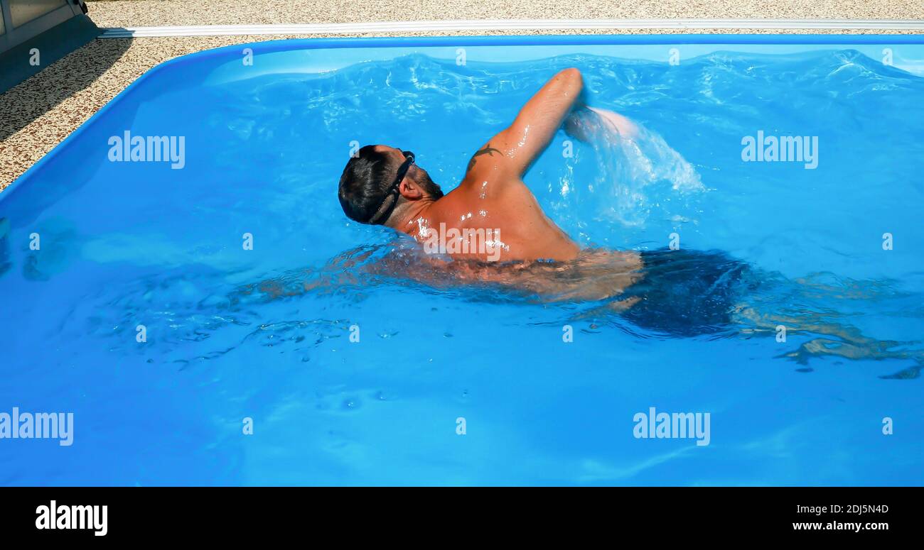 A young man trains in a home pool. Athlete swims in countercurrent ...