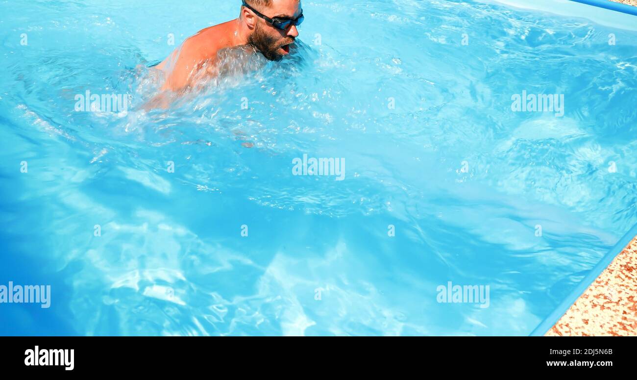 A young man trains in a home pool. Athlete swims in countercurrent ...