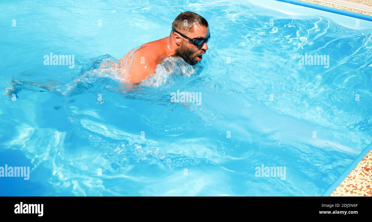 A young man trains in a home pool. Athlete swims in countercurrent ...