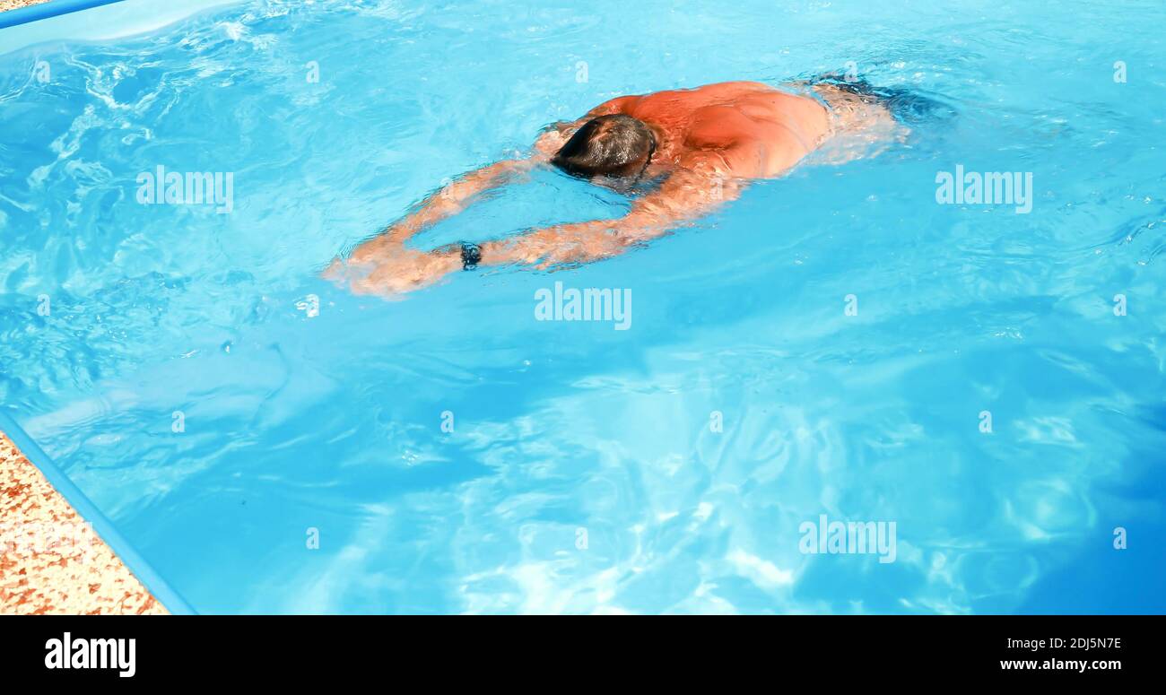 A young man trains in a home pool. Athlete swims in countercurrent ...