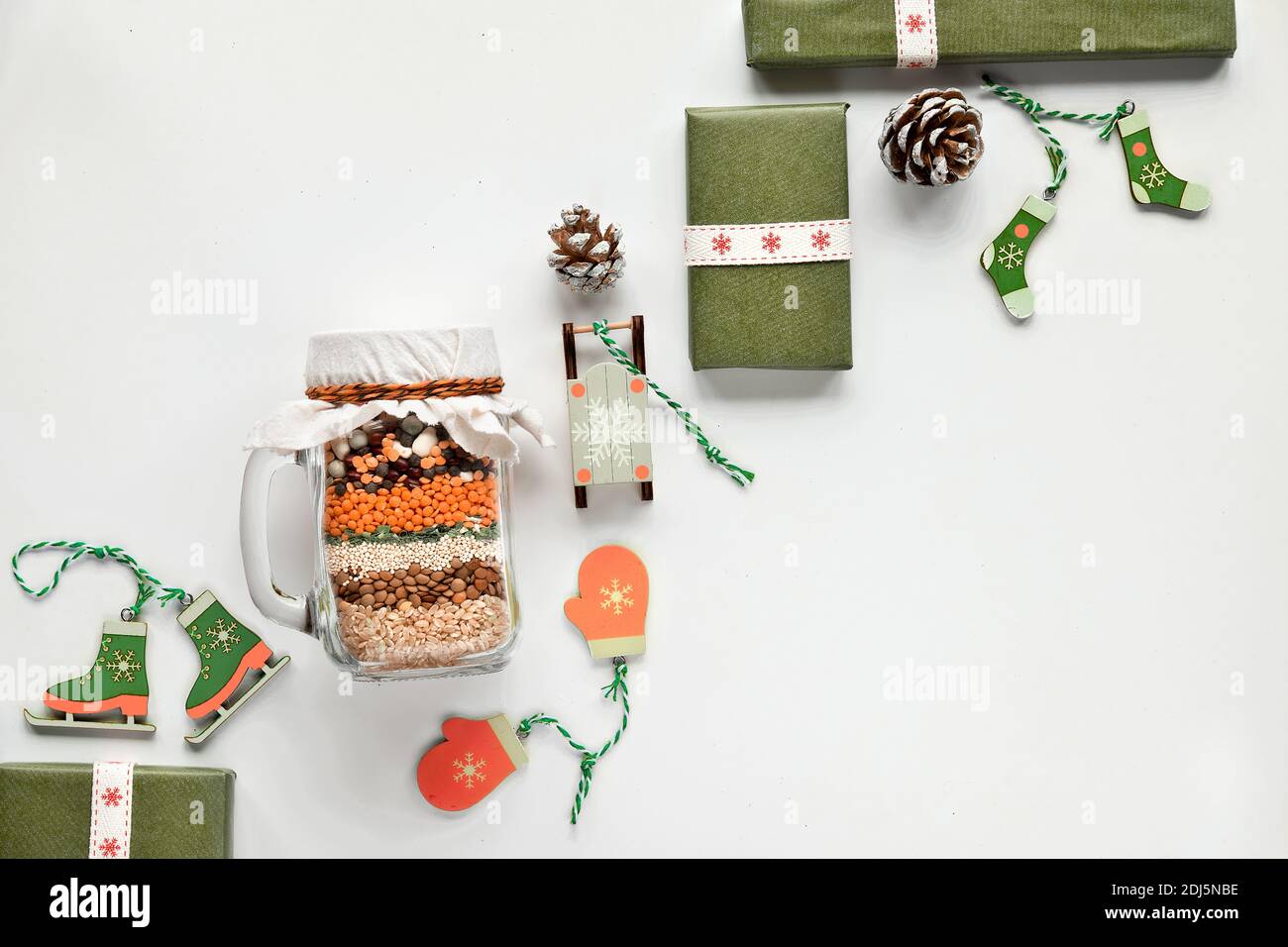 Zero waste Christmas gift in a jar. Layered bean mixture with spices on soft white textile background with no plastic wooden winter Xmas decorations Stock Photo