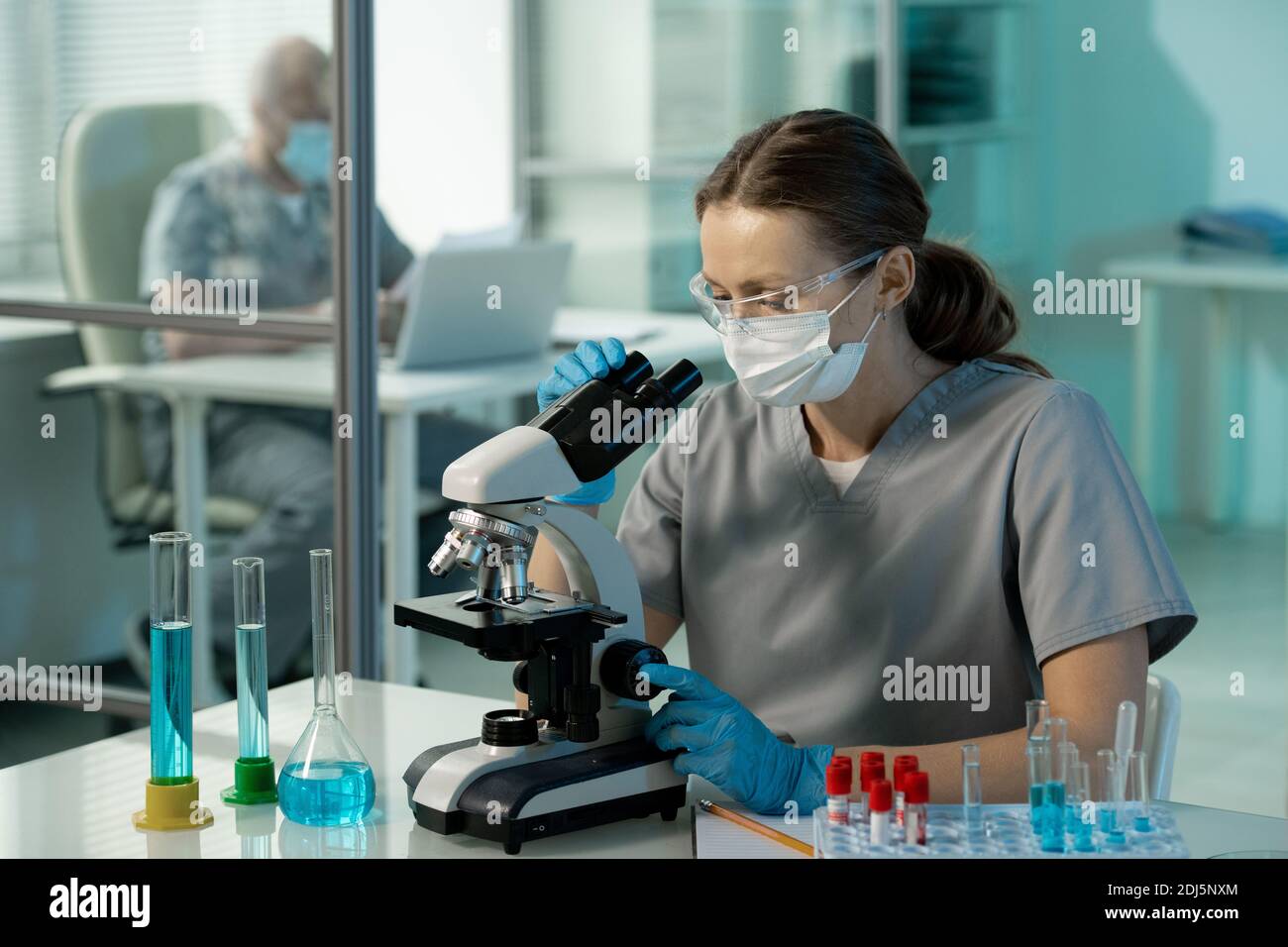 Young contemporary female scientist in uniform, protective mask and ...