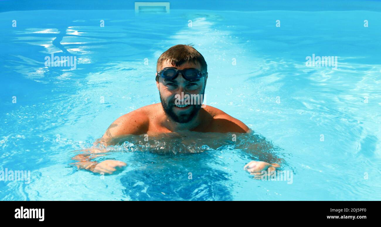 A young man trains in a home pool. Athlete swims in countercurrent ...