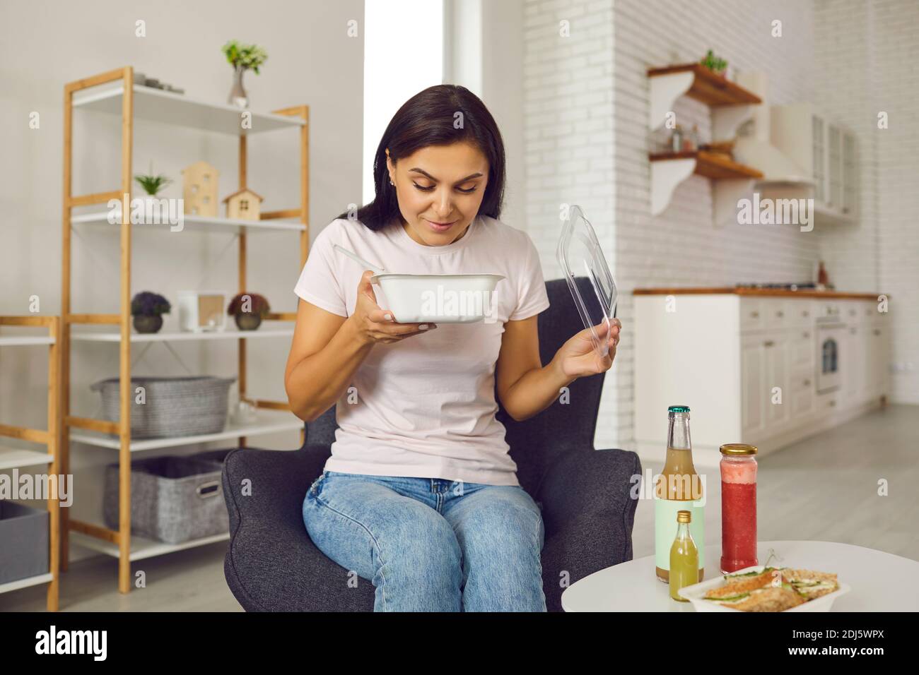 Happy young woman opening container with fresh takeaway lunch and smelling the food Stock Photo