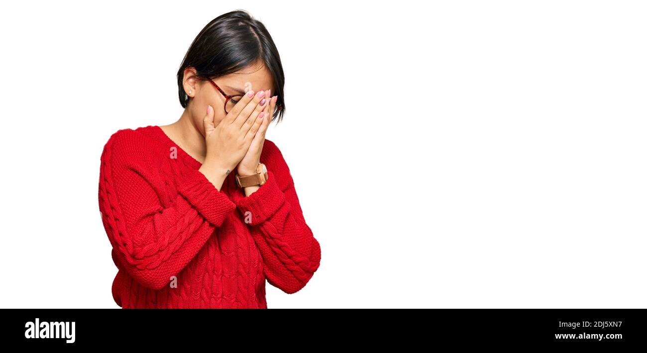 Young beautiful hispanic woman with short hair wearing casual sweater and glasses with sad expression covering face with hands while crying. depressio Stock Photo