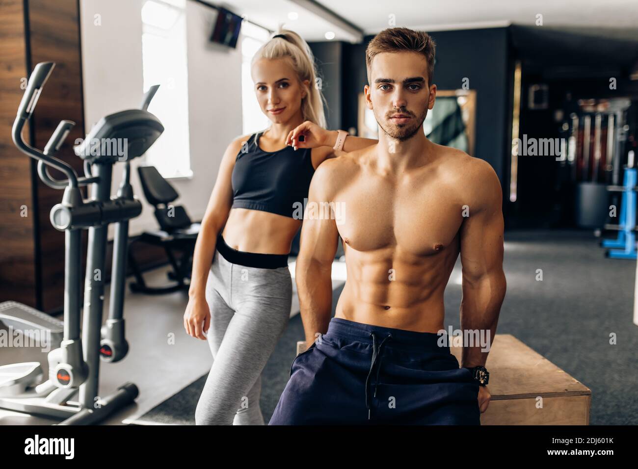Sporty young couple, woman and muscular man, in sportswear in the gym Stock Photo