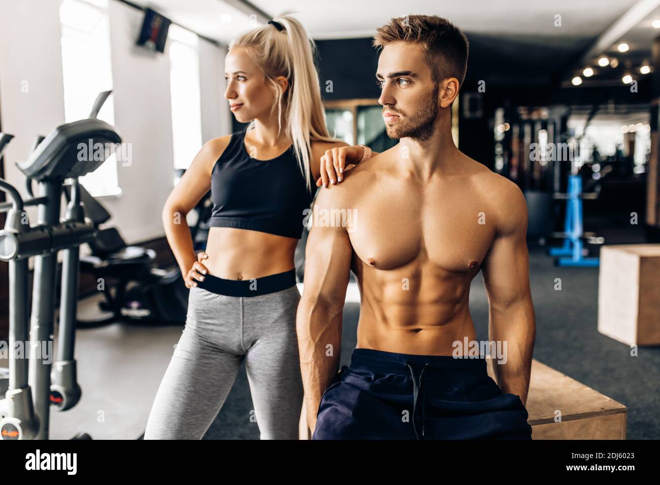 Sporty young couple, woman and muscular man, in sportswear in the gym Stock Photo